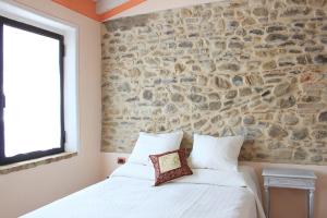 a bedroom with a stone wall and a white bed at Agriturismo Ca' Preda in San Giorgio Piacentino