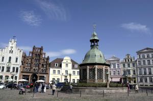a group of people walking around a city with buildings at Ferienwohnung Just City in Wismar +10 photos