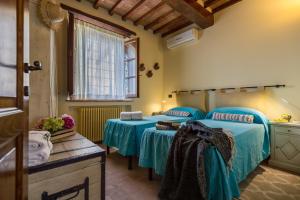 1 dormitorio con 2 camas con sábanas azules y ventana en Casina La Graziosa, en Cortona