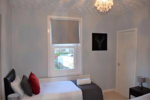 1 dormitorio con 1 cama con ventana y lámpara de araña en Kelpies Serviced Apartments - Wallace en Falkirk