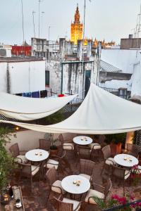 un patio con tavoli, sedie e tenda bianca. di Hotel Boutique Corral del Rey a Siviglia