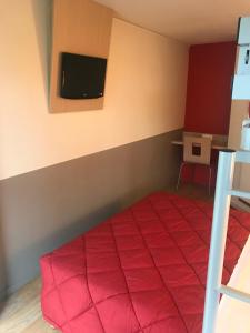 a bedroom with a red bed with a tv on the wall at Premiere Classe Montbeliard - Sochaux in Sochaux