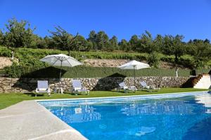 a swimming pool with two umbrellas and two chairs and a pool at Quinta da Timpeira in Lamego