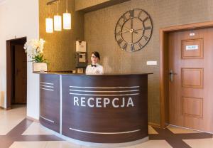 a woman standing behind a reception counter in a hotel lobby at Hotel Pod Jesiotrem in Łabiszyn