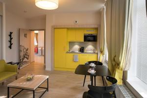 uma sala de estar com uma cozinha amarela e uma mesa em Domitys Le Carillon d'or em Maubeuge