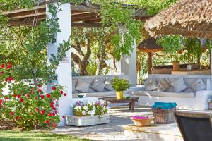 un patio con sofás blancos, flores y árboles en Hacienda de San Rafael, en Las Cabezas de San Juan