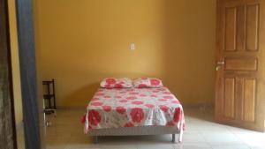 a bedroom with a bed with a red and white blanket at Pousada das Estrelas in Joanes