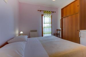 a bedroom with a bed with white sheets and a window at Anka in Nerezine