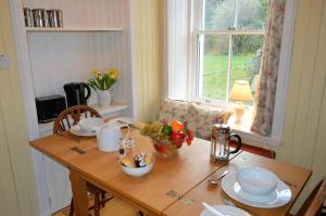 a wooden table with a bowl of fruit on it at Glenbranter Cottage in Strachur