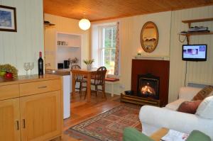 a living room with a fireplace and a kitchen with a table at Glenbranter Cottage in Strachur