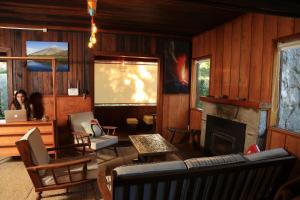 a woman sitting in a living room with a fireplace at Lucky's Hostel in Pucón