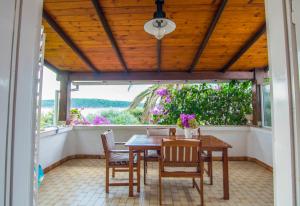 a porch with a wooden ceiling and a table and chairs at Apartments Picolo Paradiso Miljenko Debelić in Rab