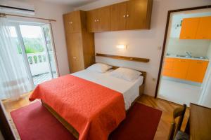 a bedroom with a bed with an orange blanket at Apartments Picolo Paradiso Miljenko Debelić in Rab