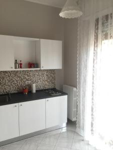 una cucina con armadi bianchi, lavandino e finestra di S'Oronzo Modern Town House a Lecce