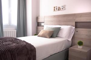 a bedroom with a large white bed with a wooden headboard at ConK Apartments by CasaTuristica in Ronda