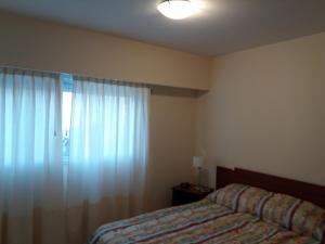 a bedroom with a bed and a window with curtains at Como en Casa 2 in Rosario