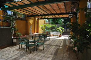 un patio con tavoli e sedie sotto un pergolato in legno di Hotel Salus a Montecatini Terme