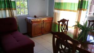 Golden Apple Cottage في Castara: غرفة معيشة مع طاولة طعام وكرسي