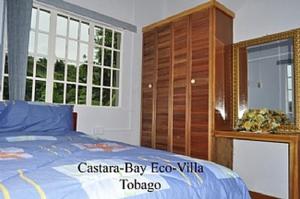 Golden Apple Cottage في Castara: غرفة نوم بسرير وخزانة خشبية
