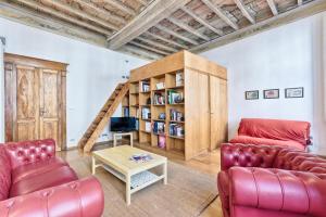 トリノにあるLoft dei Mercantiのリビングルーム(赤い革製家具、本棚付)