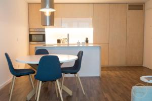 a kitchen with a white table and blue chairs at Oporto Ceuta Residences - Residence 6 by We Do Living in Porto