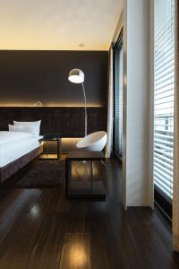 a bedroom with a bed and a chair and a lamp at SAKS Urban Design Hotel Kaiserslautern in Kaiserslautern