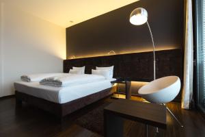 ein Schlafzimmer mit einem Bett, einem Schreibtisch und einer Lampe in der Unterkunft SAKS Urban Design Hotel Kaiserslautern in Kaiserslautern