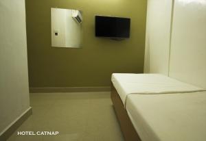 a room with two beds and a tv on the wall at Hotel Catnap in Mettuppālaiyam
