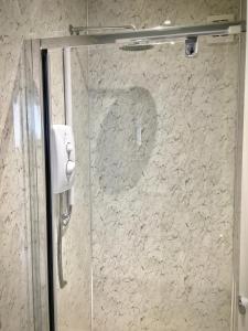 a glass shower door with a phone on a wall at Lagan Backpackers in Belfast