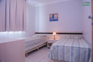 a bedroom with two beds and a table with a lamp at Prime Hotel Águas da Serra in Rio Quente +70 photos