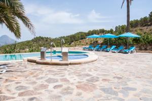 uma piscina com cadeiras azuis e guarda-sóis em Finca El Almendral em Relleu