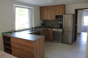 a kitchen with wooden cabinets and a stainless steel refrigerator at Vila Lom in Velké Losiny