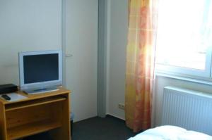 
a bedroom with a bed, desk and television at Hotel Ernst Ludwig in Darmstadt
