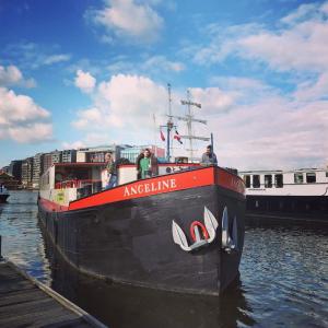 a small boat is docked in the water at Hotelboat Angeline in Amsterdam