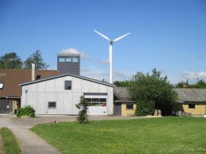 a white building with a wind turbine in the background at Fuglsang Apartments in Skattebølle
