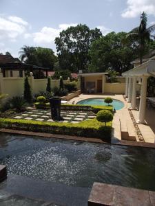 un patio trasero con piscina y una casa en La Barune Guest House, en Tzaneen