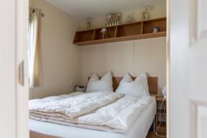 CHALETS IN THE DUNES nearby the beach في آيماودن: غرفة نوم بسرير ذو شراشف ووسائد بيضاء
