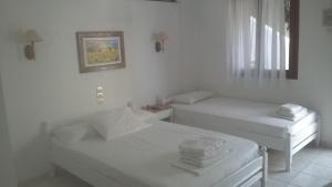 a white room with two beds and a window at Aeolos Hotel Apartments in Gythio