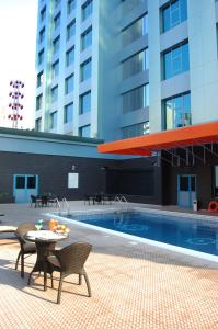 麥納麥的住宿－The Olive Hotel, Juffair，一座带椅子和桌子的游泳池位于一座建筑旁边