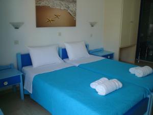 Una cama azul con dos toallas blancas. en Ikonomakis Apartments, en Balíon