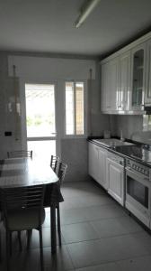 a kitchen with white cabinets and a table with chairs at Apartamentos Loyo in Portomarin