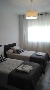 a bedroom with two beds and a chandelier at Apartamentos Loyo in Portomarin