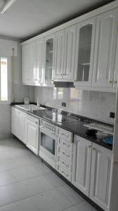kuchnia z białymi szafkami i czarnymi blatami w obiekcie Apartamentos Loyo w mieście Portomarin