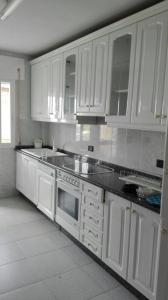 a kitchen with white cabinets and white appliances at Apartamentos Loyo in Portomarin