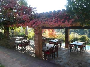 a patio with tables and chairs under a pergola with pink flowers at Can Barrina in Montseny
