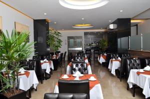 a restaurant with white tables and black chairs at Hotel 5 de Mayo in Puebla
