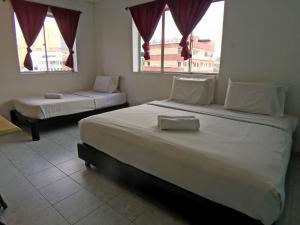 a bedroom with two beds and two windows at Abell Residence in Kuching