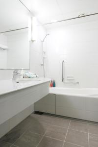 a white bathroom with a sink and a tub at Haneda Excel Hotel Tokyu Haneda Airport Terminal 2 in Tokyo