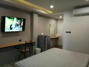 a bedroom with a bed and a desk and a tv on the wall at Sor Kor Sor Resort in Sattahip