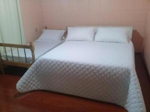 a bed with white sheets and pillows in a room at Del Fiore in Gramado